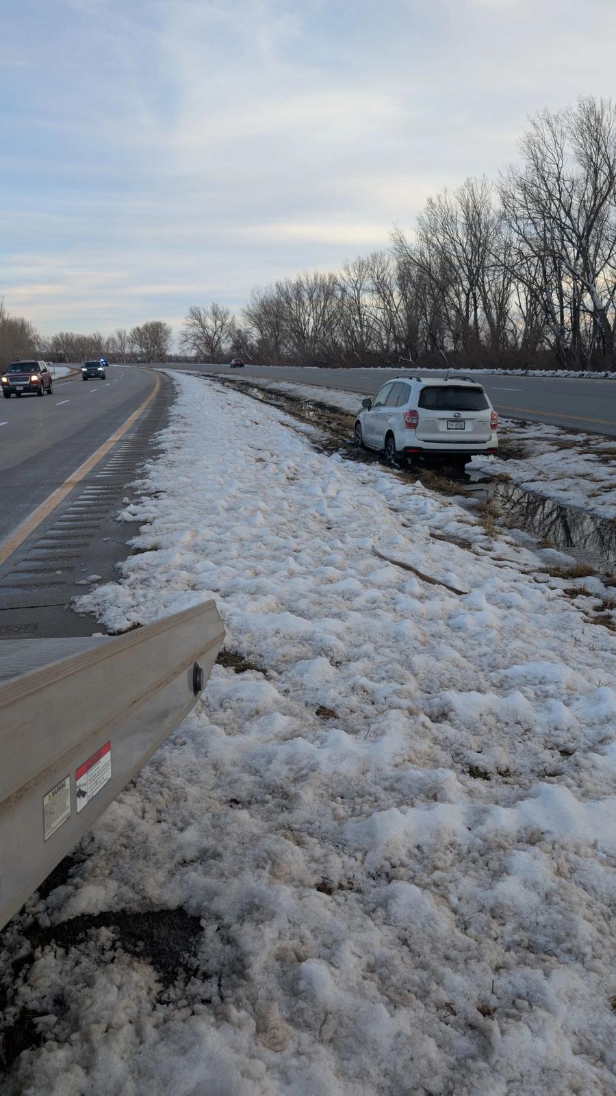 White SUV off the road in a snowy ditch beside a Nebraska highway before a Calhoun Transport recovery