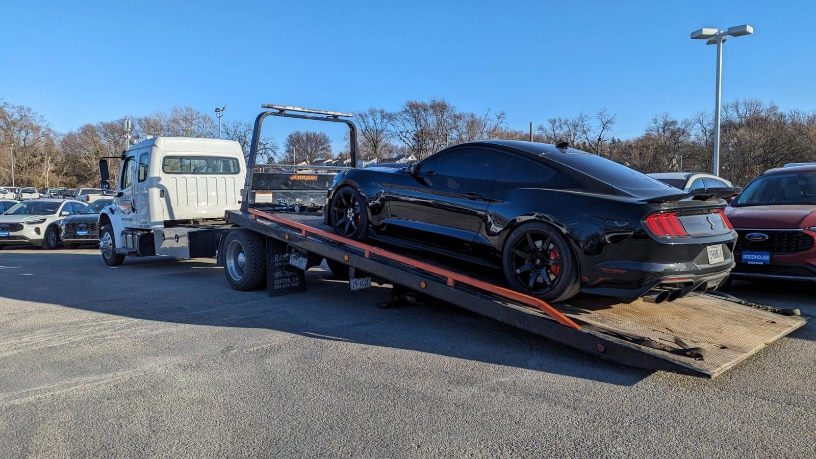 Black Shelby GT350 Mustang loaded on a Calhoun Transport flatbed at a Nebraska Ford dealership